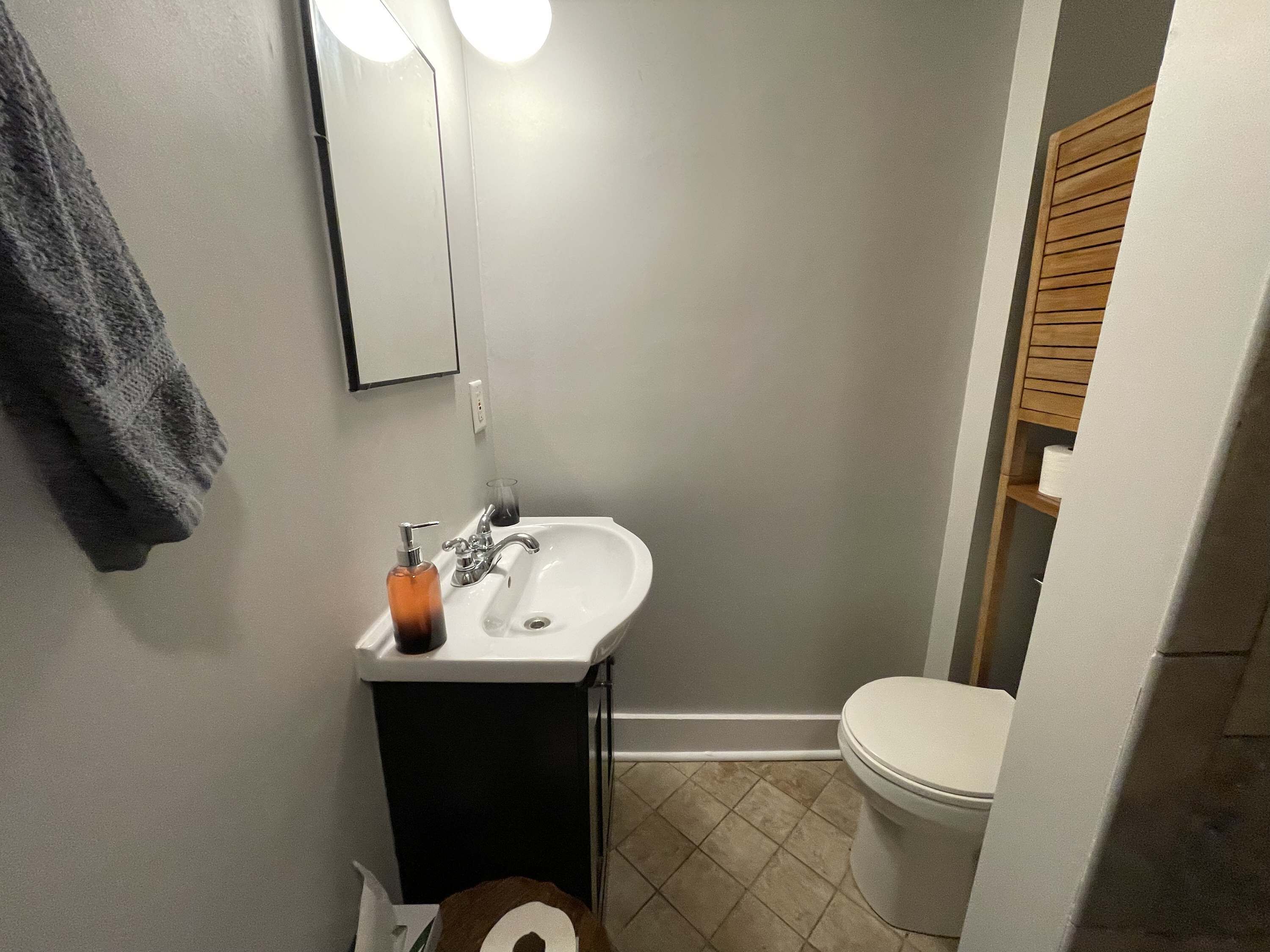 A bathroom with a white sink, a mirror, a towel hanging on the wall, and a toilet.