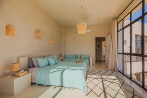 Ein Schlafzimmer mit einem großen Bett, einem Nachttisch mit Lampe und Blick durch ein großes Fenster.