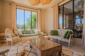 A spacious living room with a sofa, armchair, and a coffee table. - Lalla Essaouira, Villa Khmissa, piscine chauffée et personnel (Essaouira)