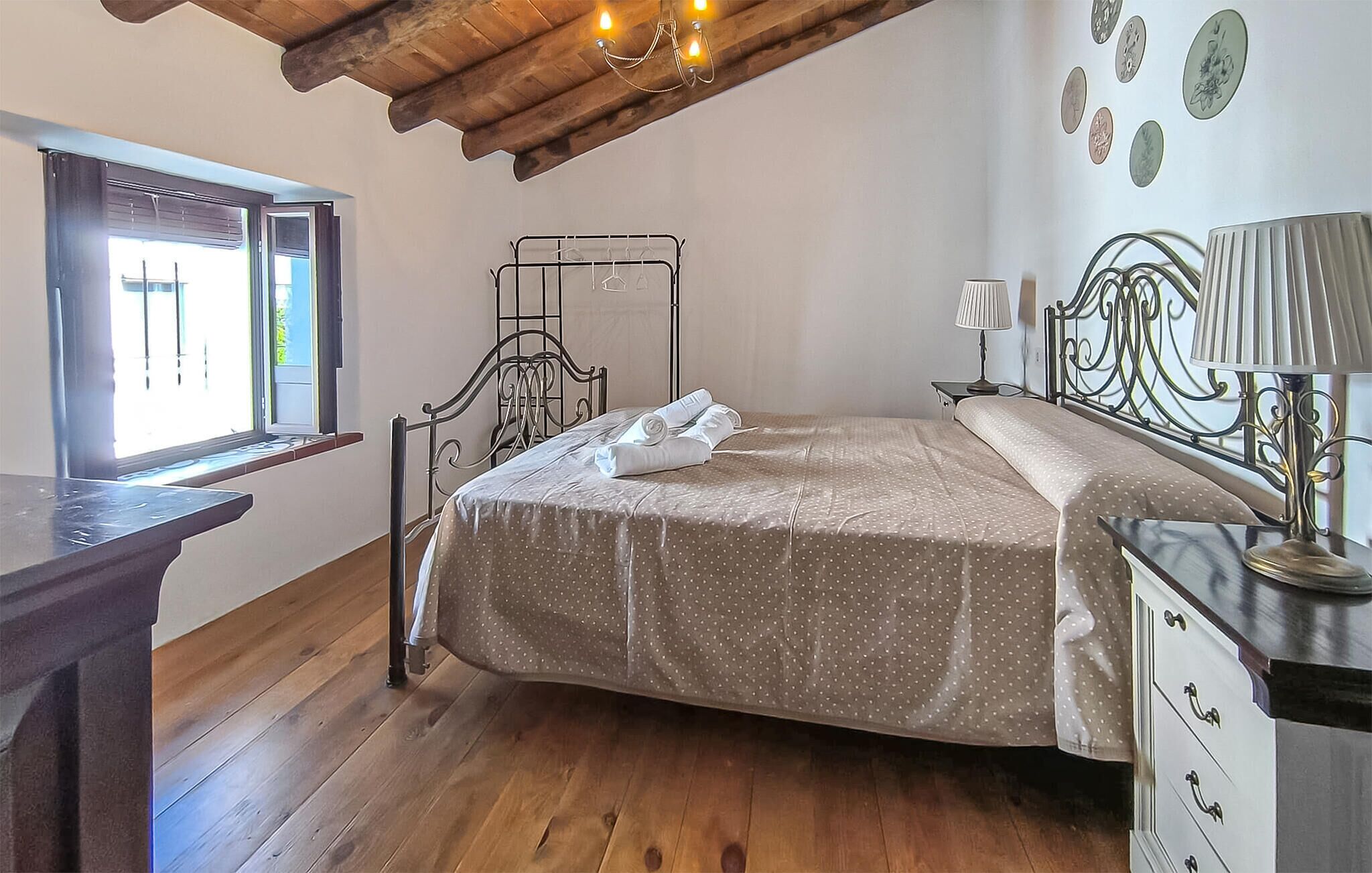 Une chambre à coucher avec un lit, une table de chevet, une lampe et une fenêtre avec des stores.