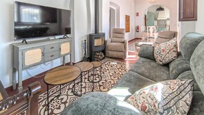 A living room with a television, sofa, armchairs, patterned floor, and a fireplace. - Awesome home in Castilblanco de los Ar (Castilblanco de los Ar)