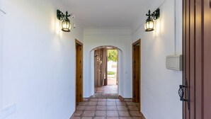 Un corridoio con pavimento piastrellato, due porte in legno e luci a parete.