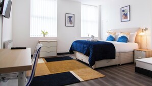 A modern bedroom with a bed, bedside tables, a desk, and a chair. - Residency apartments liverpool (Bootle)