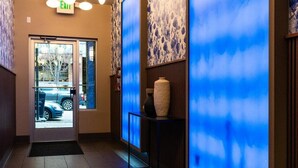 Un hall d’hôtel avec un comptoir d’accueil, un mur éclairé en bleu et un luminaire au plafond.
