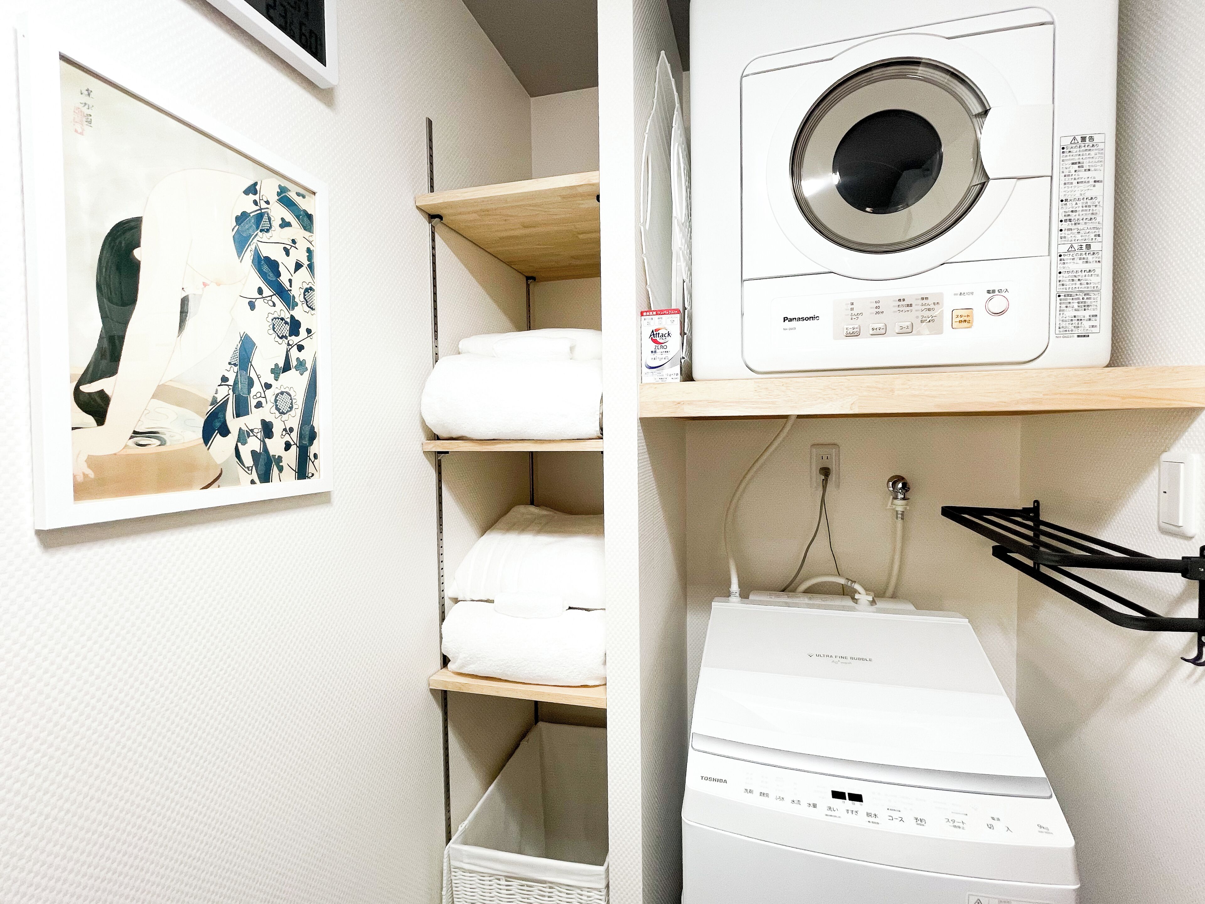 A laundry area with a washing machine, a dryer, and shelves with folded towels.