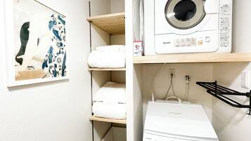 A laundry area with a washing machine, a dryer, and shelves with folded towels.