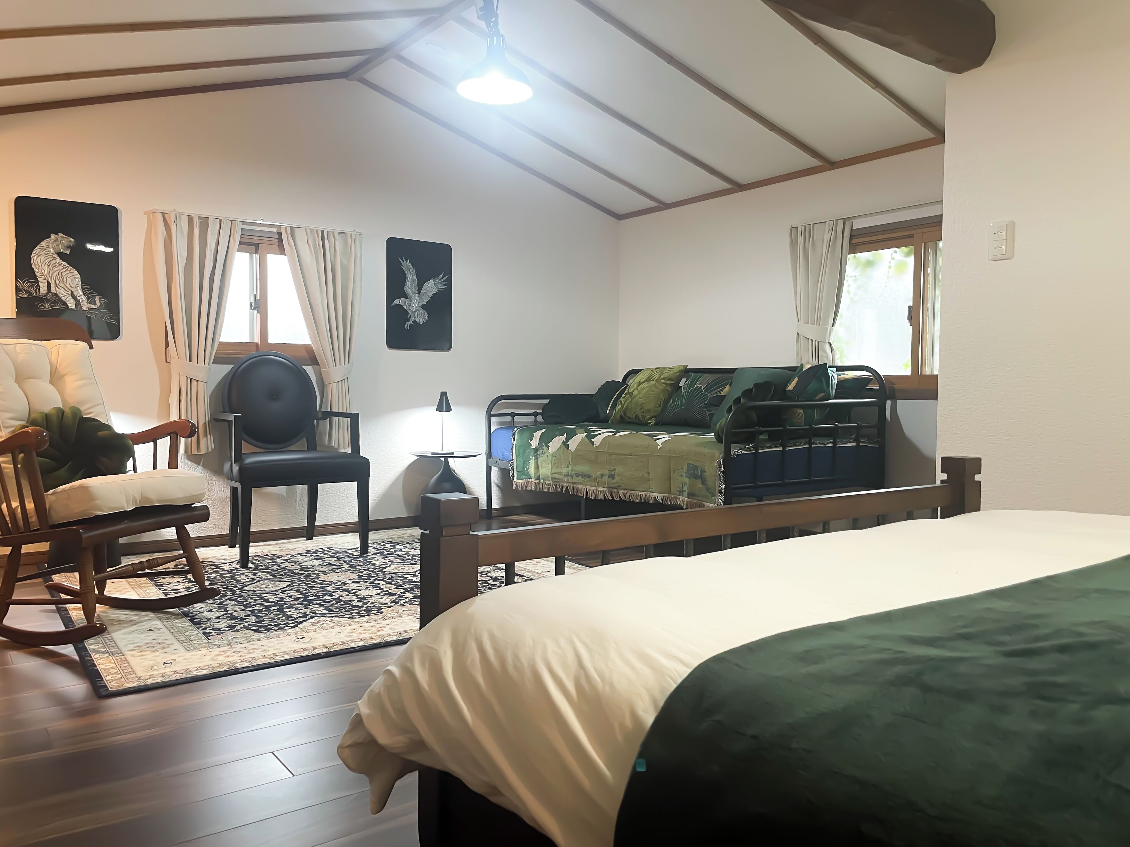 A cozy room with a bed, a rocking chair, a sofa, and a small table.