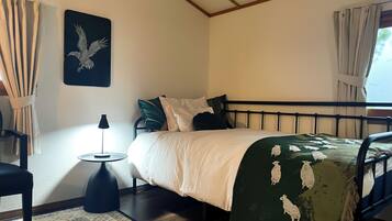 A neatly arranged bedroom with a bed, a small side table, a lamp, and a decorative wall piece.