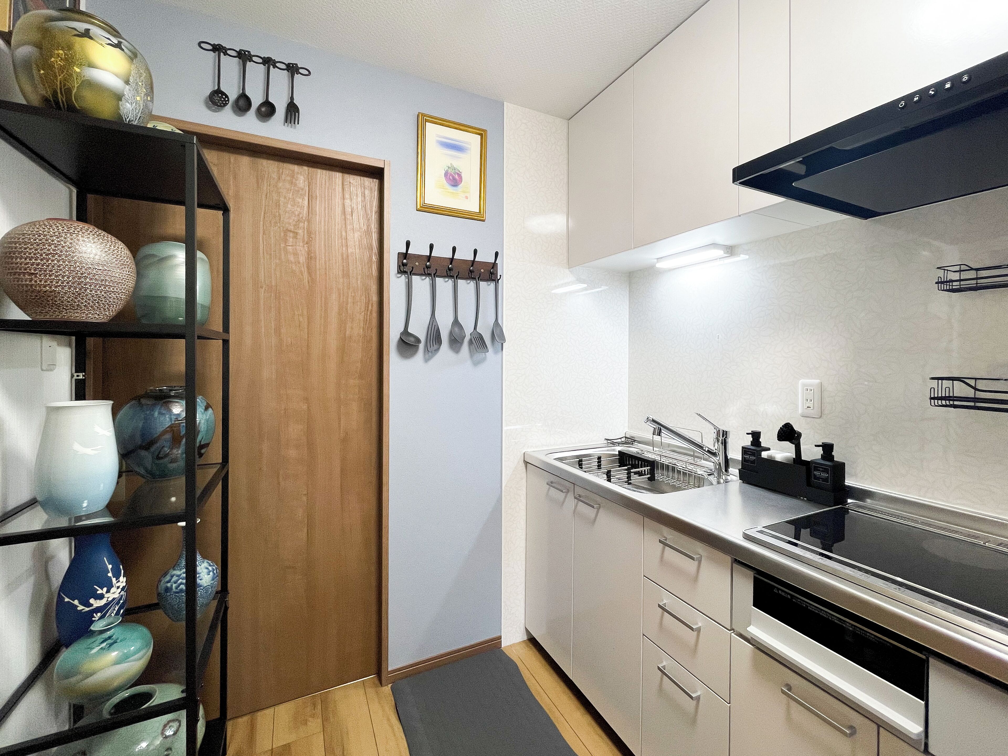 A modern kitchen with white cabinets, a stainless steel sink, and a black range hood.