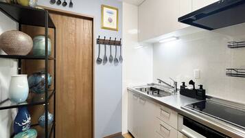 A modern kitchen with white cabinets, a stainless steel sink, and a black range hood.