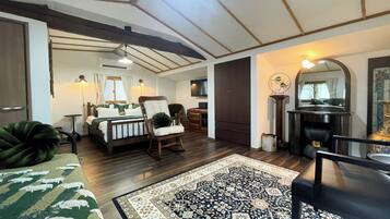 A cozy room with a bed, a rocking chair, a large rug, and a mirror.