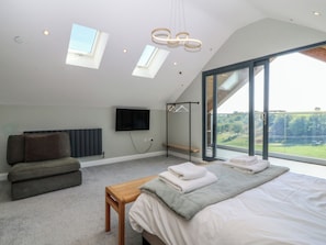 Une chambre à coucher avec un lit, un canapé, une télévision et une grande fenêtre.