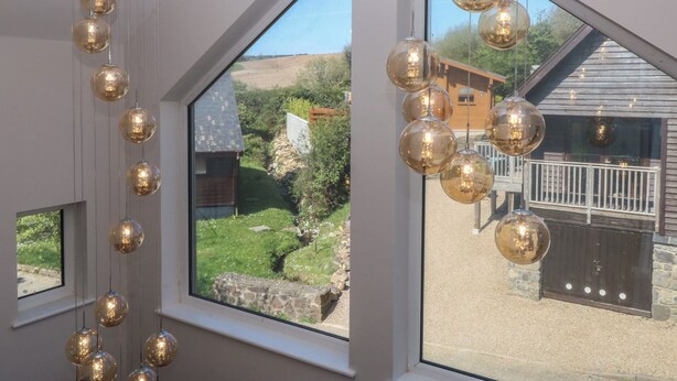 Una habitación con ventanas amplias, una lámpara colgante y vistas a un paisaje rural.