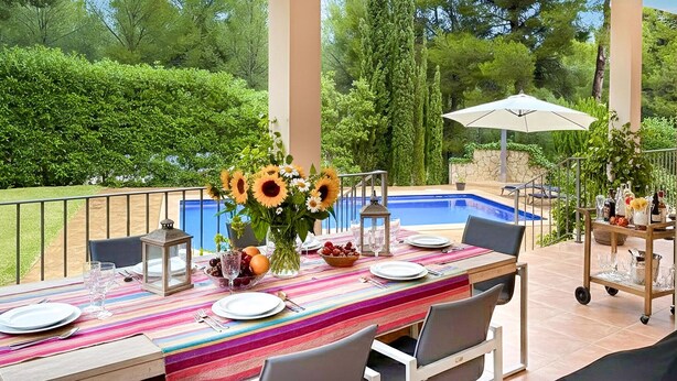 Un espace extérieur aménagé pour les repas, avec une piscine, le tout entouré d’une végétation luxuriante.