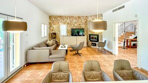 Un salon moderne avec un mur en pierre, un canapé, un téléviseur et une cheminée.
