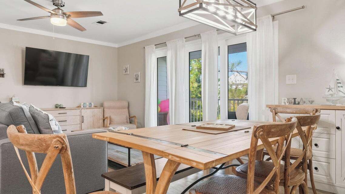 Una sala de estar moderna con una mesa de comedor de madera, un sofá y un televisor montado en la pared.