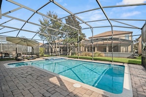 Ein Swimmingpool mit Glaskuppel, umgeben von einer Terrasse mit Sitzgelegenheiten und einem überdachten Bereich.