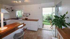 Een moderne keuken met witte kasten, een houten aanrechtblad en een raam met uitzicht op een tuin.