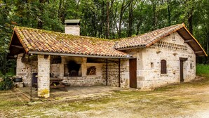 Ein rustikales Steinhaus mit Ziegeldach, Schornstein und einer kleinen Veranda.