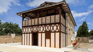 Un bâtiment traditionnel en pierre, doté d’un balcon en bois et d’une enseigne indiquant « Le Rivoir ».