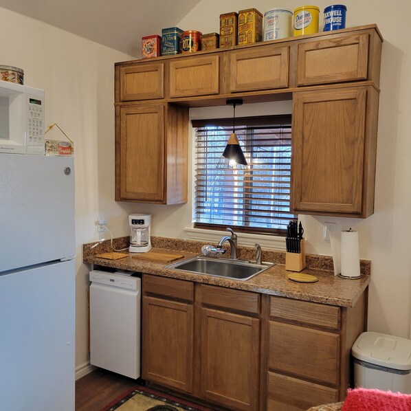 A kitchen with wooden cabinets, a stainless steel sink, a coffee maker, and a microwave.