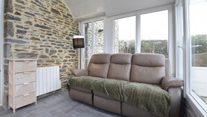 Een zonnedek met een stenen muur, een bank, een houten kast en een radiator.