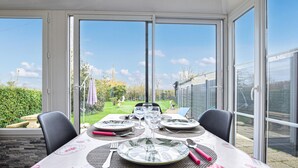 Een eettafel voor vier personen, met uitzicht op een tuin door grote ramen.