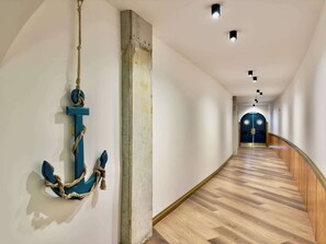A hallway with a wooden floor, a blue anchor decoration, and a double door at the end. - The Wesley Playas de Tijuana Storybook by the sea (Tijuana)