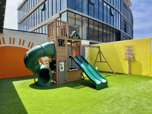 Ein Spielbereich für Kinder mit Rutsche, Klettergerüst und einem Holzschild.