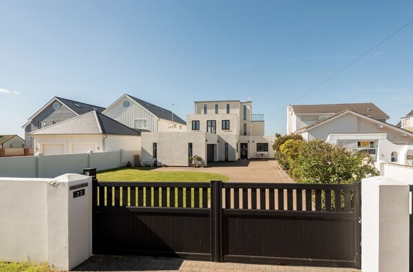 A residential area with modern houses, a gated entrance, and a well-maintained lawn.