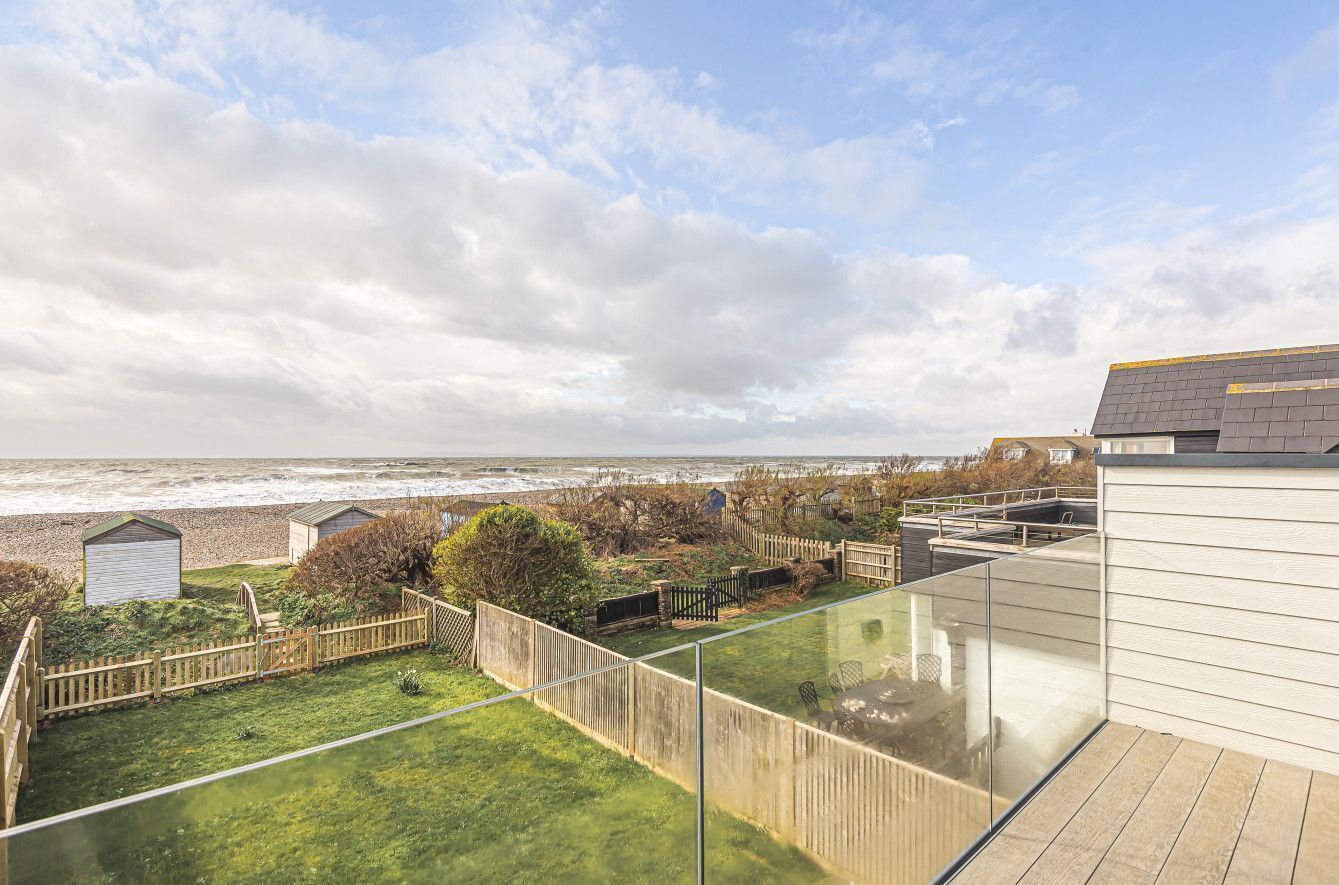 Un bâtiment moderne doté d’un balcon en verre donnant sur une plage.