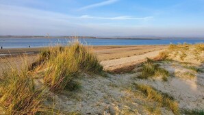 A beach with sand dunes and a calm sea. - Beira Mar Beachfront Family Home | Pet-Friendly, Sleeps 8, Parking Included (East Wittering)