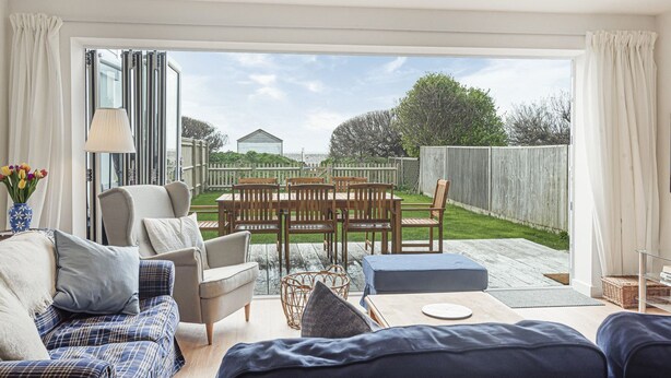 A spacious living room with a large sliding glass door leading to a patio area. - Beira Mar Beachfront Family Home | Pet-Friendly, Sleeps 8, Parking Included (East Wittering)