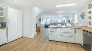 A modern kitchen with white cabinetry, a central island, and a wooden countertop. - Beira Mar Beachfront Family Home | Pet-Friendly, Sleeps 8, Parking Included (East Wittering)