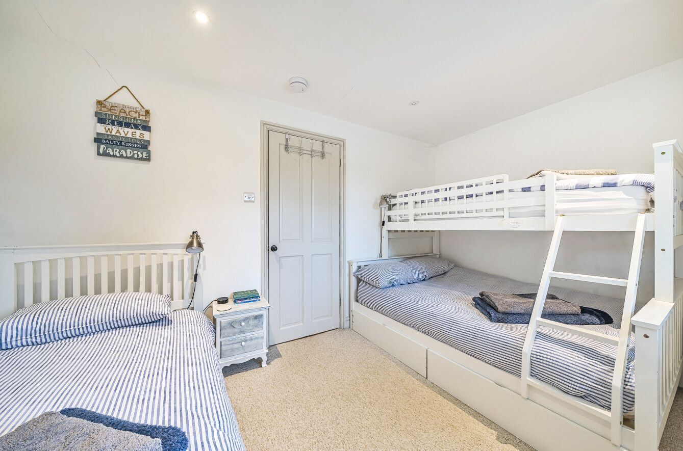 Een slaapkamer met twee stapelbedden, een nachtkastje, een lamp en een deur.