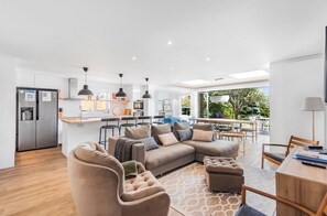 Una sala de estar moderna con un sofá modular, otomanas y un comedor con una mesa y sillas de madera.