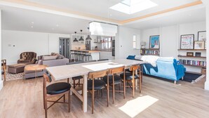 Ein geräumiger Wohnbereich mit Esstisch, Sofas und einer Küche im Hintergrund.