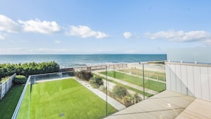 Un balcone con vista libera sull'oceano e un prato curato.