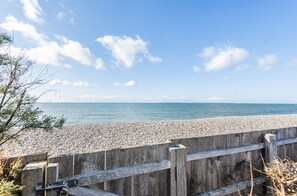 A wooden boardwalk leading to a pebble beach with a clear view of the sea. - Samphire: Stunning Seafront Beach Home – Sleeps 6, 3 Bedrooms & Garden (West Wittering)