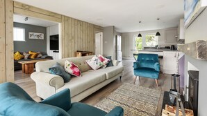 Een moderne woonkamer met een bank, stoelen en een open haard.