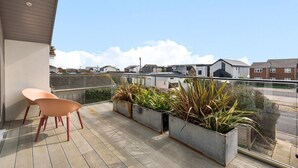 Een balkon met twee stoelen en bloempotten, met uitzicht op een woonwijk.
