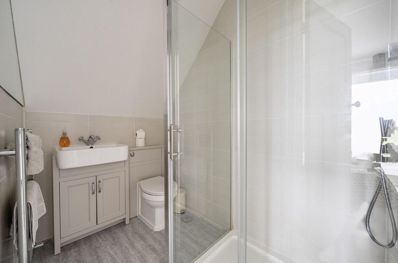 A modern bathroom with a glass-enclosed shower, a white sink, and a toilet.