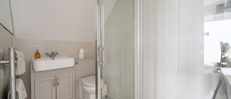 A modern bathroom with a glass-enclosed shower, a white sink, and a toilet.