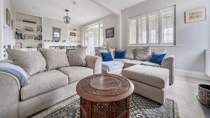 A modern living room with two sofas, a coffee table, and a bookshelf. - Seacote: Family Seafront Home in Selsey – Sleeps 7, Hot Tub & Sea Views (Selsey)