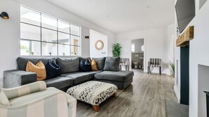 Una sala moderna con un sofá modular, un reposapiés estampado y un sillón a rayas.