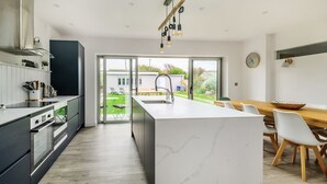 Una cocina moderna con una isla grande, electrodomésticos integrados y vistas a un jardín.