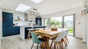 Una cocina moderna con una isla central, armarios blancos y azul marino, y un tragaluz.