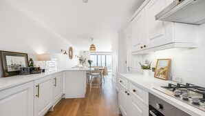 Una cocina moderna con muebles blancos, una isla central y un comedor con vistas.