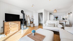 Una sala de estar moderna con chimenea, televisor de pantalla plana, cómoda de madera y sofá blanco.