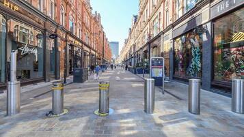 A street with shops on either side, bollards in the middle, and a clear sky.